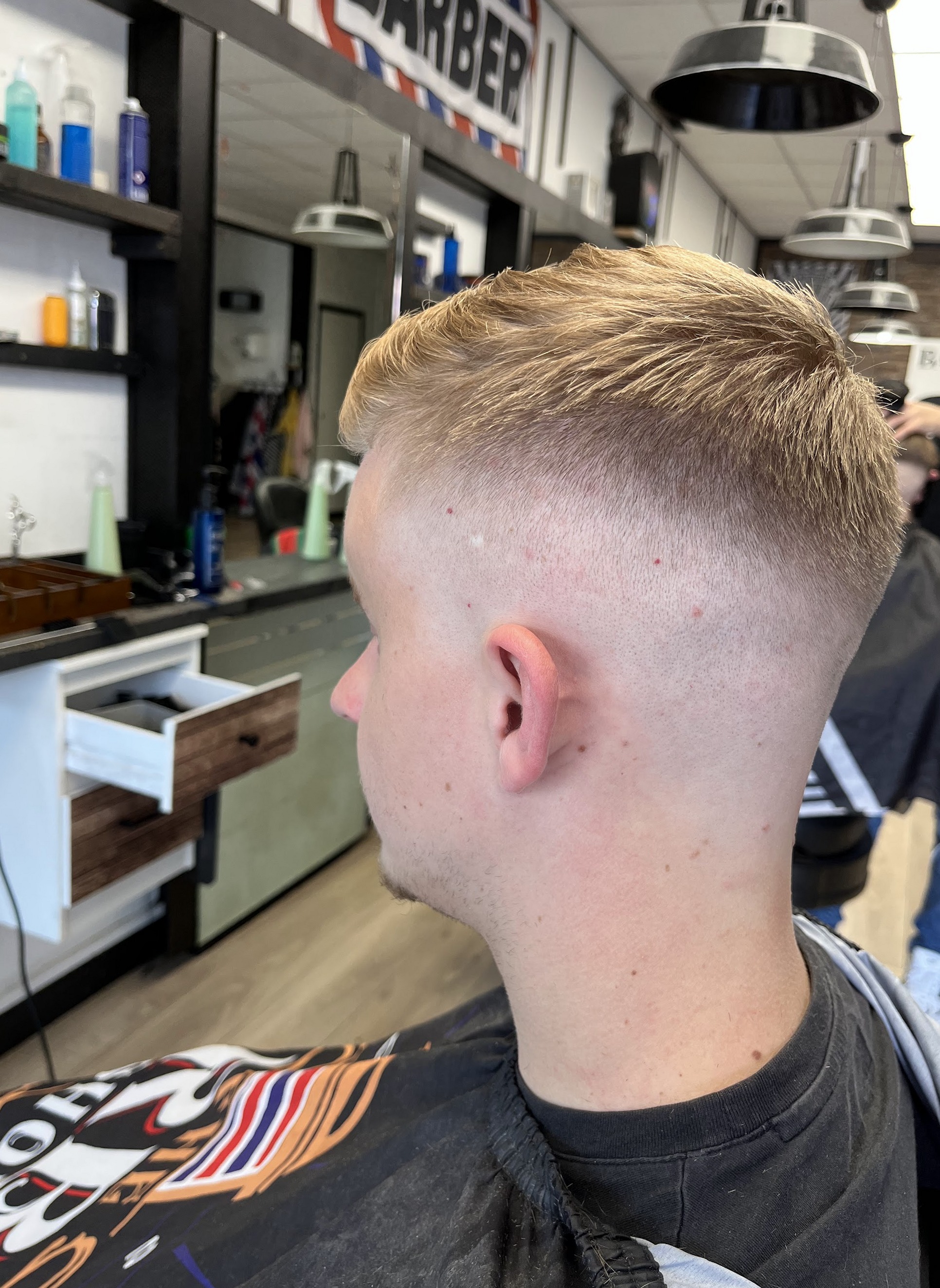 Skin fade met blond haar bovenop, van opzij gezien